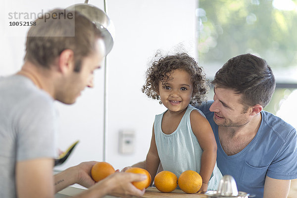 Schwules Paar mit Tochter macht Orangensaft