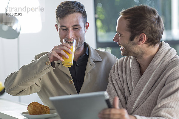 Glückliches schwules Paar mit digitalem Tablett zu Hause