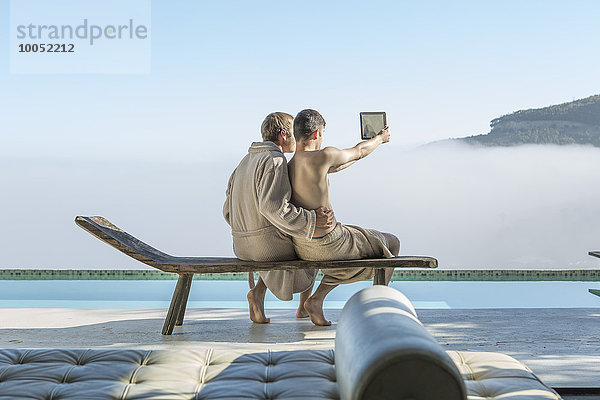 Schwules Paar am Pool mit einem Selfie mit digitalem Tablett
