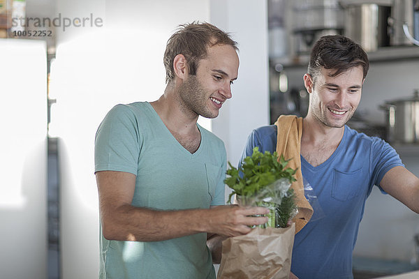 Fröhliches schwules Paar beim Kochen in der Küche