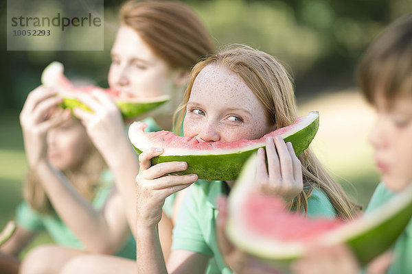 Porträt eines Mädchens  das eine Scheibe Wassermelone isst und den Jungen beobachtet.