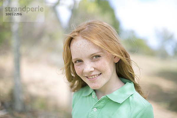 Porträt eines lächelnden Mädchens mit roten Haaren und Sommersprossen