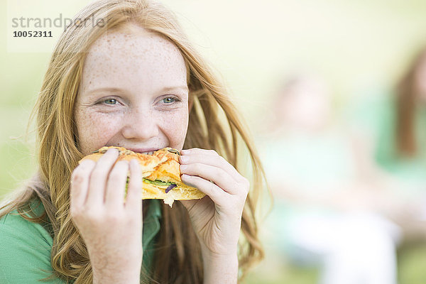 Porträt eines Mädchens mit roten Haaren  das ein Sandwich isst.