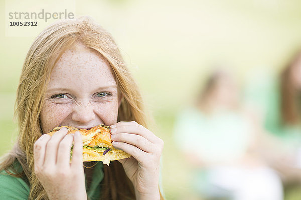 Porträt eines Mädchens mit roten Haaren  das ein Sandwich isst.