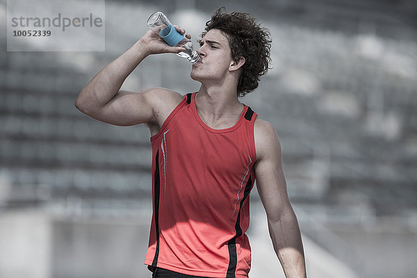 Junger Sportler trinkt Wasser
