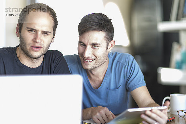 Zwei Männer mit Laptop und digitalem Tablett