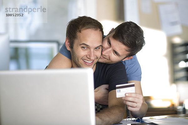 Glückliches schwules Paar mit Laptop-Shopping online