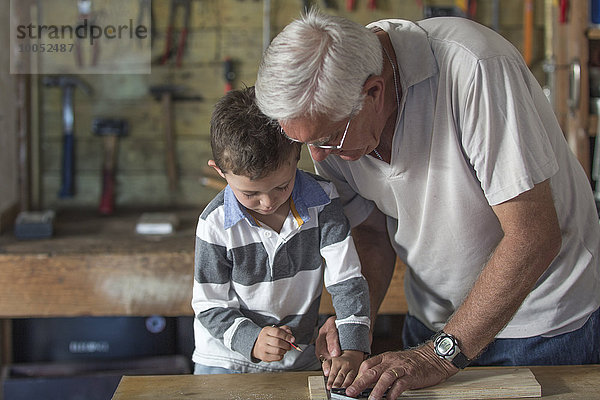 Großvater und Enkel bei der Arbeit mit Holz in einer Garage