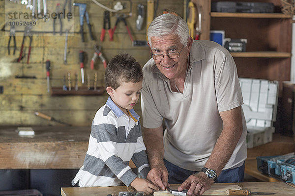 Großvater und Enkel bei der Arbeit mit Holz in einer Garage