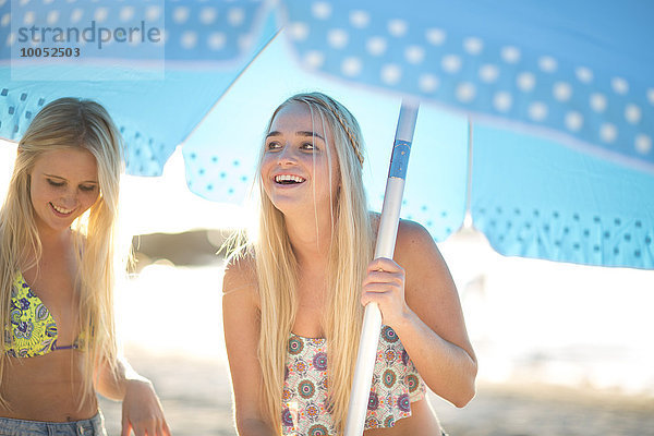 Zwei glückliche junge Frauen unter dem Sonnenschirm