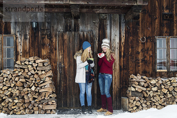 Zwei junge Freundinnen beim Plaudern vor der Holzhütte