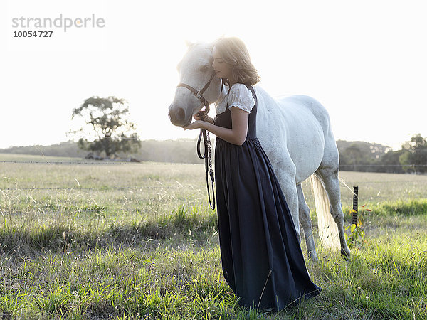 Porträt eines jungen Mädchens mit grauem Pferd im sonnigen Feld