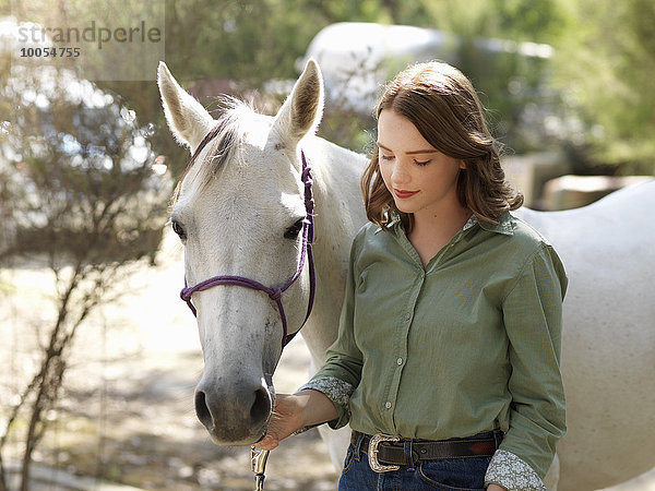 Porträt eines jungen Mädchens mit grauem Pferd auf dem Bauernhof