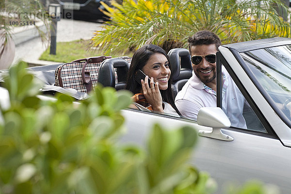 Mittleres erwachsenes Paar im Cabriolet  Frau mit Smartphone