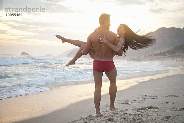Mittleres erwachsenes Paar am Strand  Mann mit Frau im Arm  Rückansicht