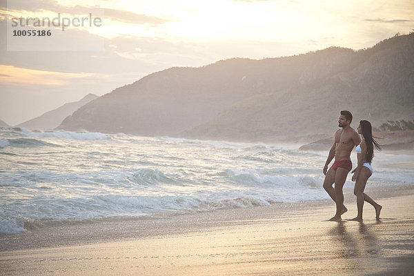 Mittleres erwachsenes Paar am Strand  in Badebekleidung  auf dem Weg zum Meer.
