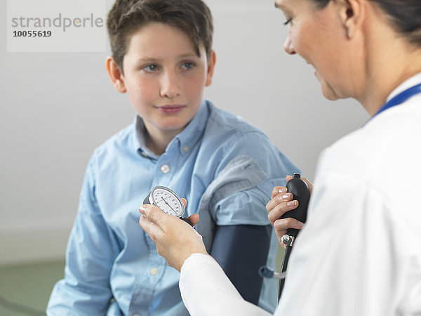 Arzt  der den Blutdruck eines kleinen Jungen in der Klinik liest