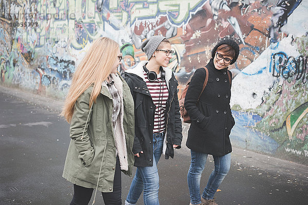 Drei Schwestern gehen durch Graffiti-Wand