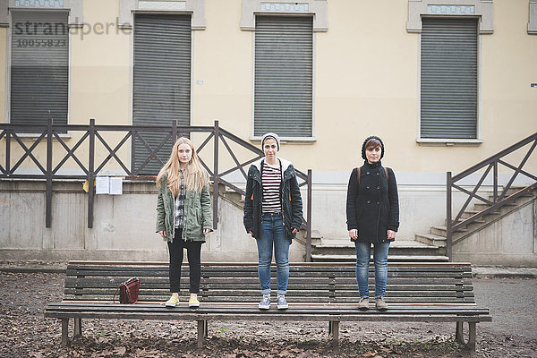 Drei Schwestern stehen auf der Parkbank