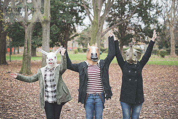 Drei Schwestern mit Tiermasken tanzen im Park