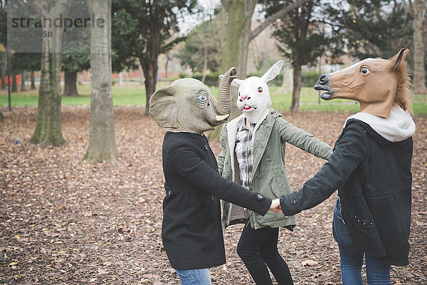 Drei Schwestern mit Tiermasken tanzen im Park
