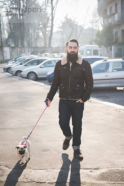 Junge bärtige Mann zu Fuß Hund auf der Straße