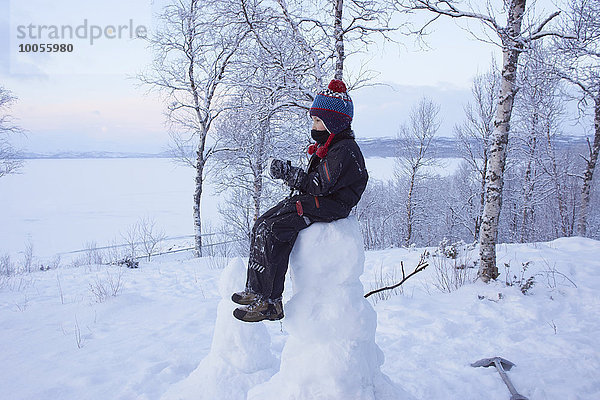 Junge sitzend auf Schneemann  Hemavan  Schweden