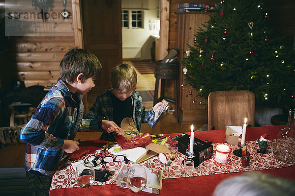 Zwei Brüder eröffnen Weihnachtsgeschenke bei Tisch