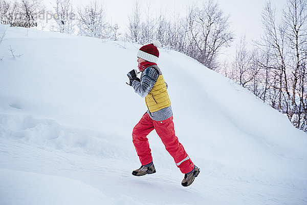 Junge rennt den schneebedeckten Hügel hinauf  Hemavan  Schweden