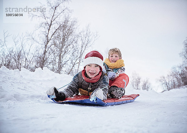 Flachwinkelansicht von zwei Brüdern auf dem Schlitten auf schneebedecktem Hügel  Hemavan  Schweden
