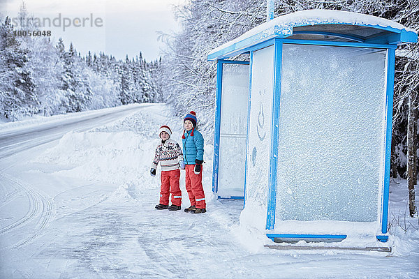 Zwei Brüder warten an der schneebedeckten Bushaltestelle  Hemavan  Schweden