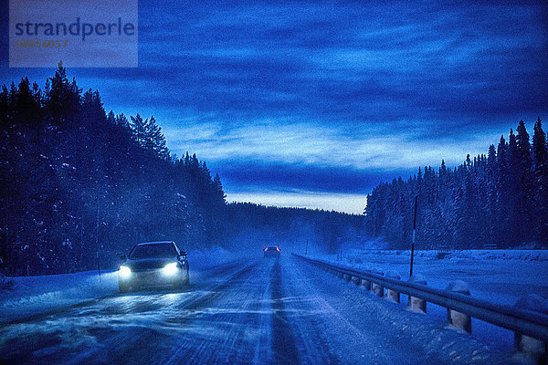 Autoscheinwerfer auf schneebedeckter Autobahn bei Dämmerung  Hemavan  Schweden