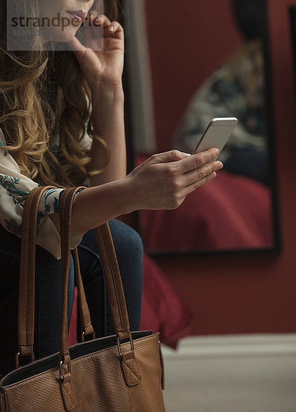 Frau betrachtet Smartphone beschnitten