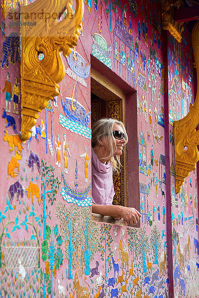 Touristin mit Blick aus dem Wat Xieng Thong Fenster  Luang Prabang  Laos