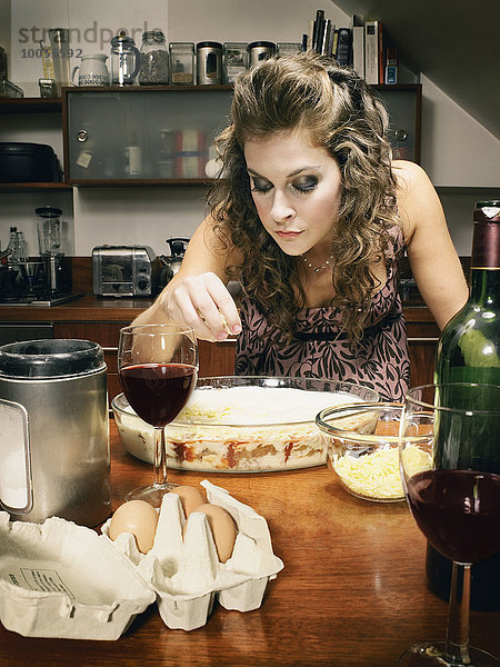 Glamouröse junge Frau  die in der Küche Käse auf den Teller streut.