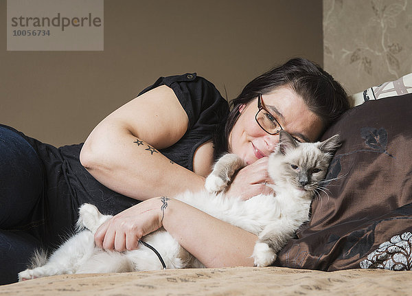 Portrait der Ragdoll-Katze mit Besitzer  entspannend im Bett