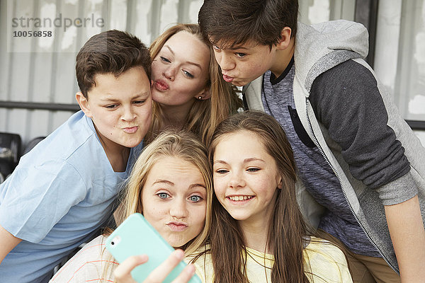 Fünf Jungen und Mädchen machen Gesichter für Smartphone Selfie im Schutzraum