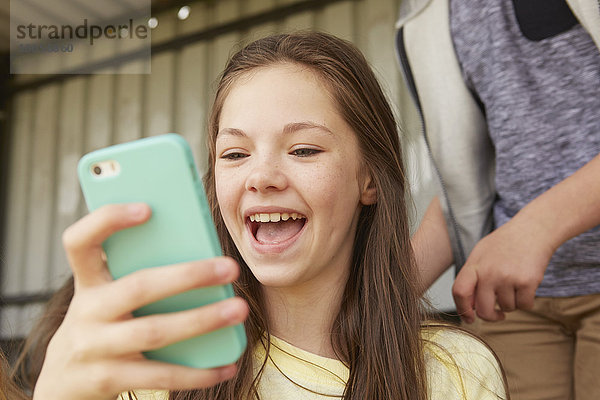 Mädchen lachen über Smartphone im Tierheim