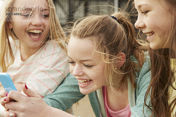 Drei Mädchen lachen über Smartphone-Text