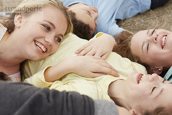 Fünf Jungen und Mädchen  die auf dem Weg liegen und lachen.