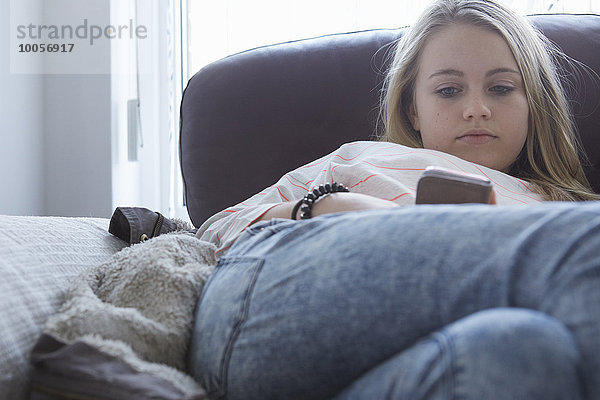 Mädchen beim Lesen von Smartphone-Texten auf dem Sofa