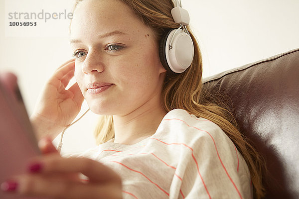 Nahaufnahme eines Mädchens auf dem Sofa  das Musik über Kopfhörer hört.