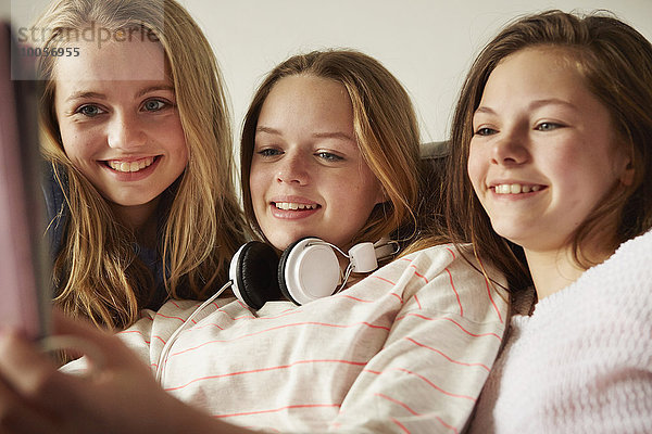 Drei Mädchen auf dem Sofa mit digitalem Tablett