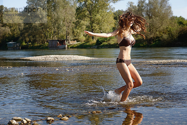 Junge Frau im Bikini beim Planschen und Spielen im Fluss