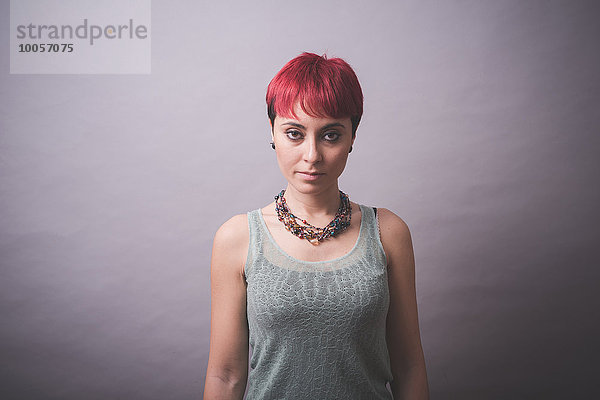 Studio-Porträt einer jungen Frau mit kurzen rosa Haaren