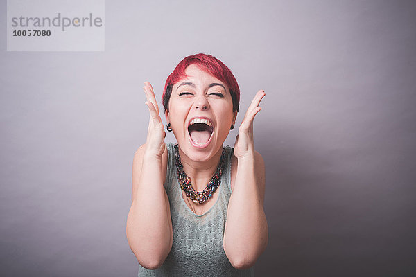 Studio-Porträt einer jungen Frau mit kurzen rosa Haaren  die lacht