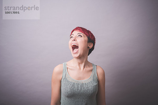 Studio-Porträt einer jungen Frau mit kurzen rosa Haaren  die schreit