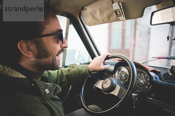 Mittlerer erwachsener Mann lächelnd beim Fahren von Oldtimern