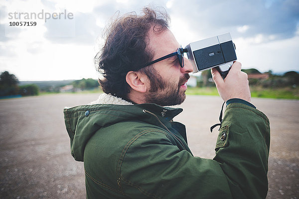 Mittlerer Erwachsener Mann mit Vintage-Filmkamera auf Brachland