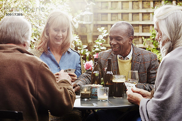 Seniorenfreunde beim Trinken und Kartenspielen im Garten